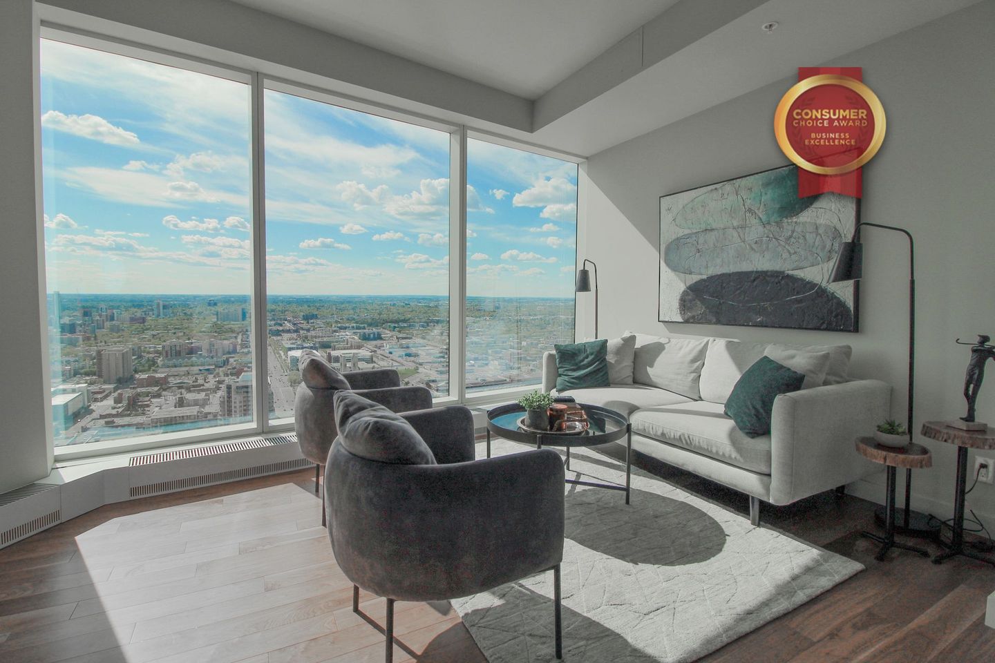 Furnished condo with ceiling to floor windows overlooking downtown Edmonton Grey couches and 2 chairs as well as other living room accessories 