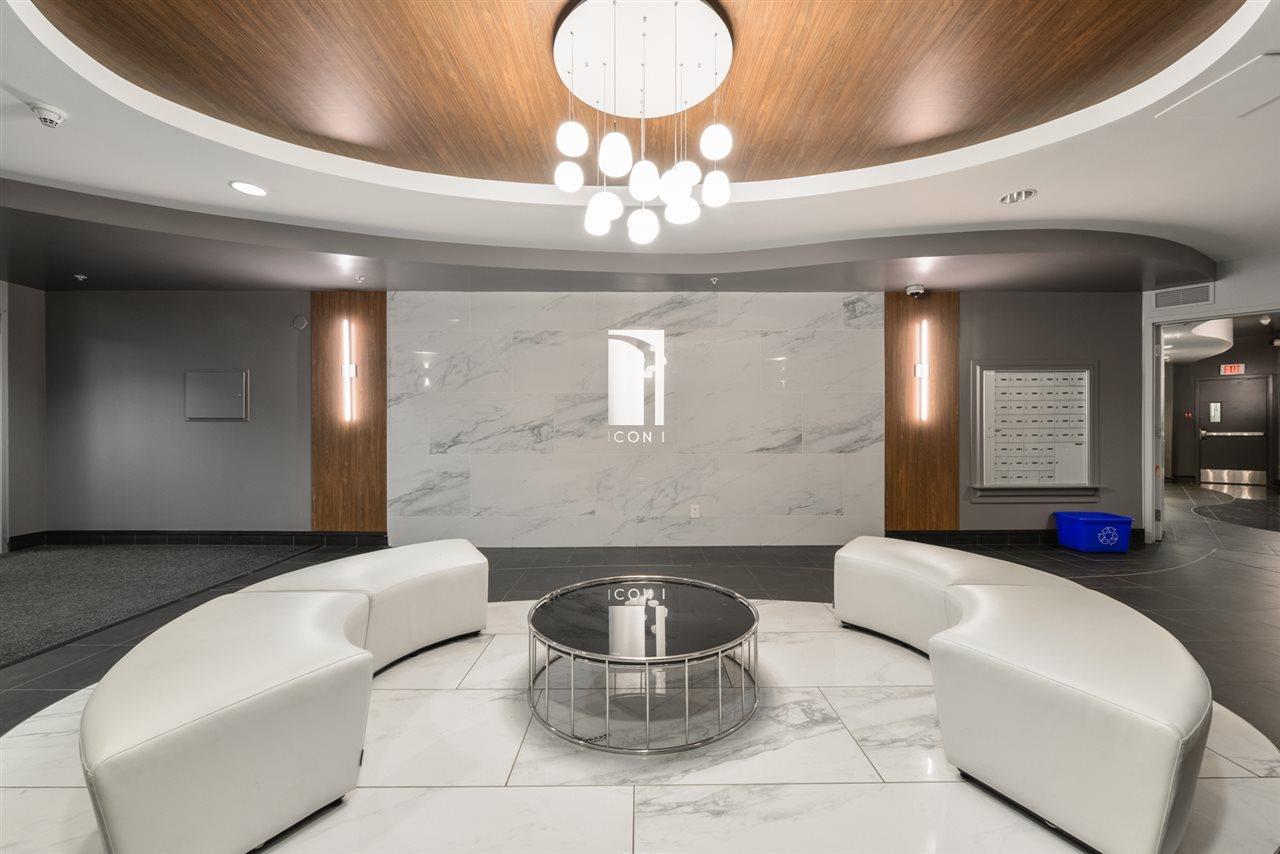 White marble lobby with  white rounded backless leather benches and a round coffer table in the centre and a