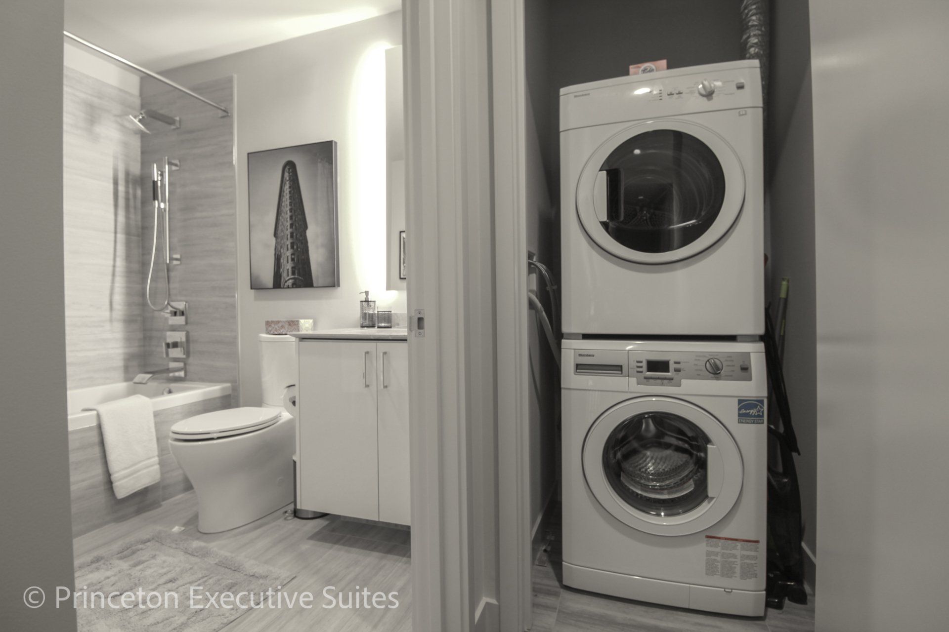 In Suite laundry with state of the art stackable washing machine in a closet next to the modern bathroom