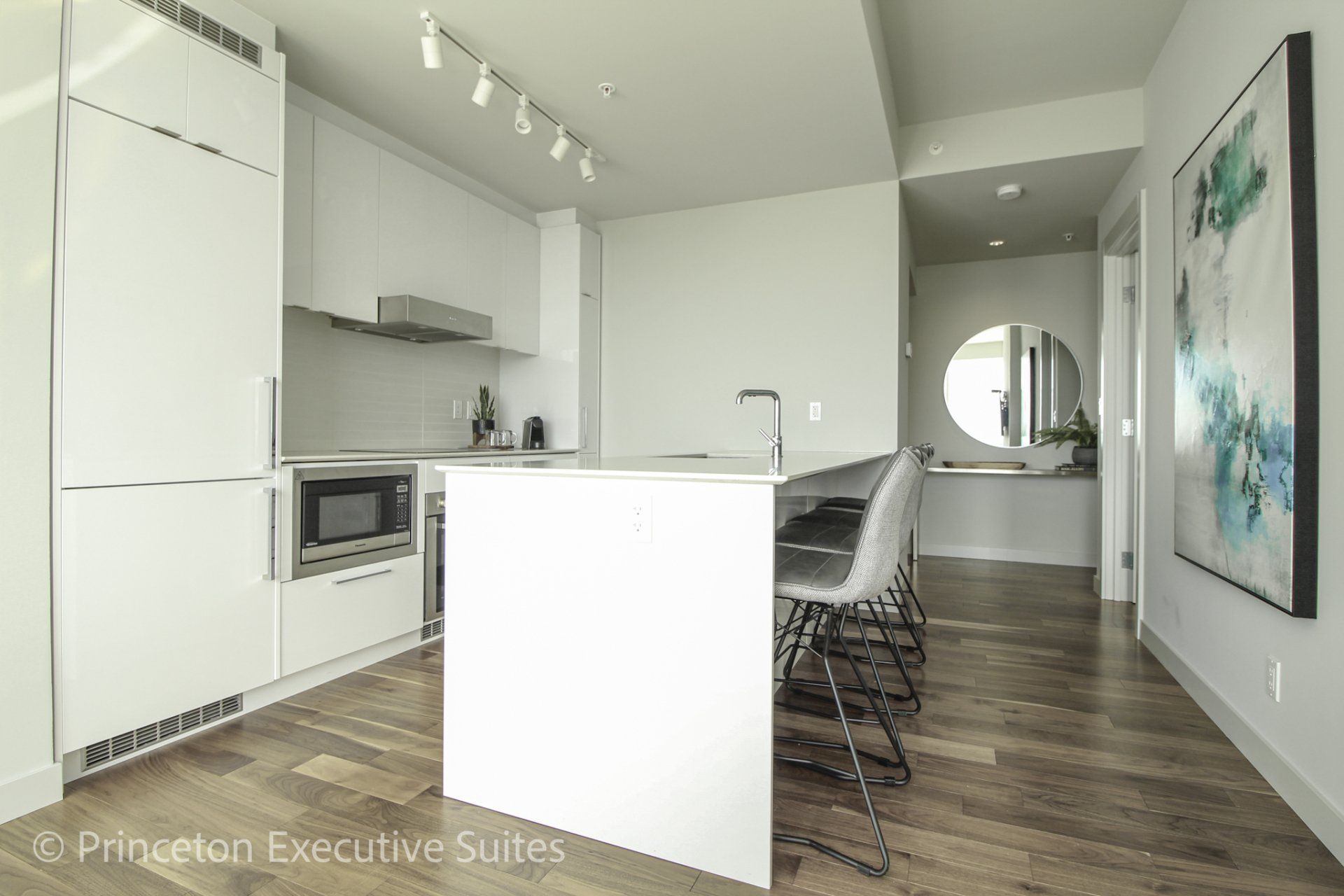 White glossy eating bar with white quartz counter tops and 4 modern barstools in front of the eating bar inside this edmonton executive furnished rental