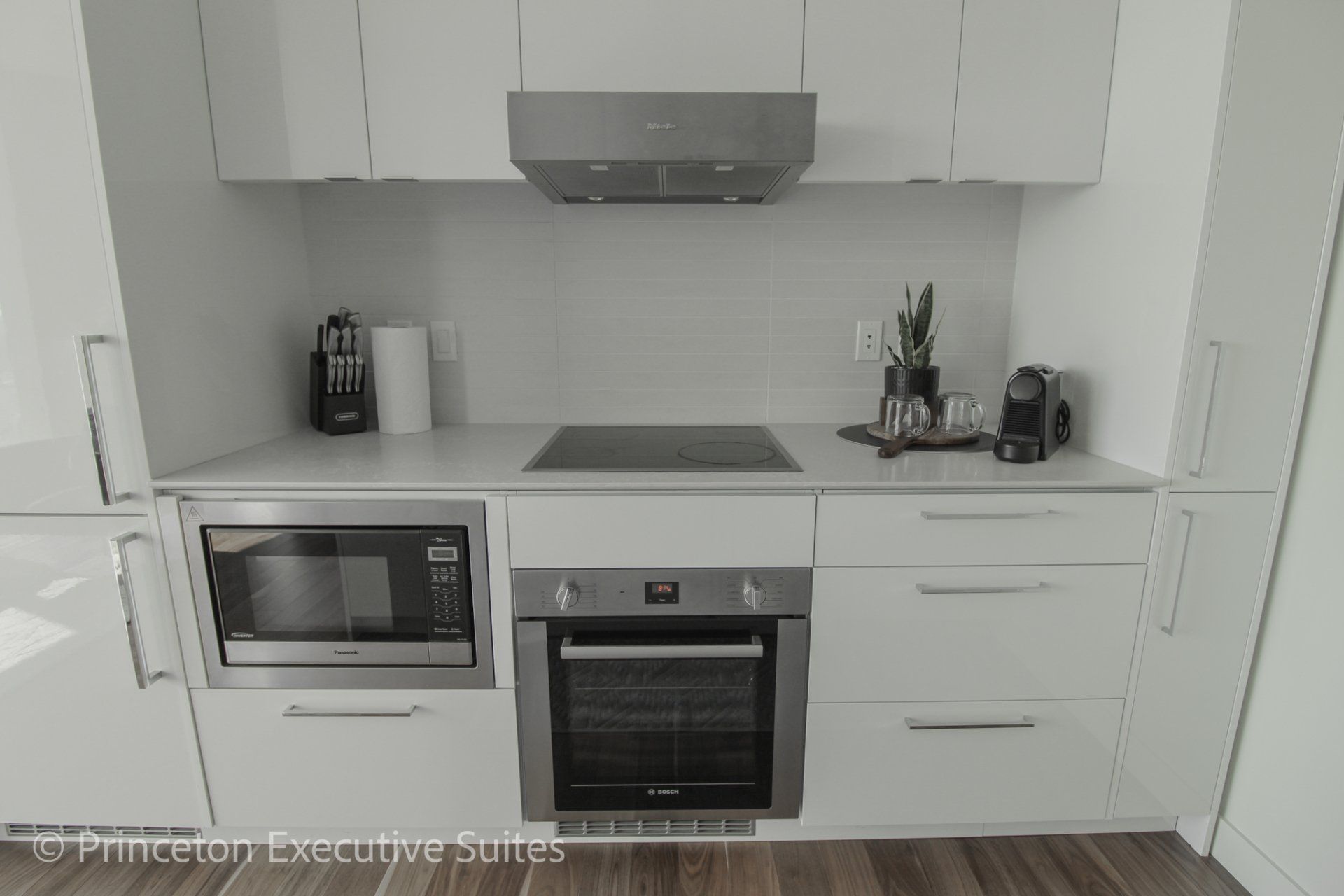Built in stainless steel ceramic cooktop with white glossy cabinets in this edmonton furnished apartment