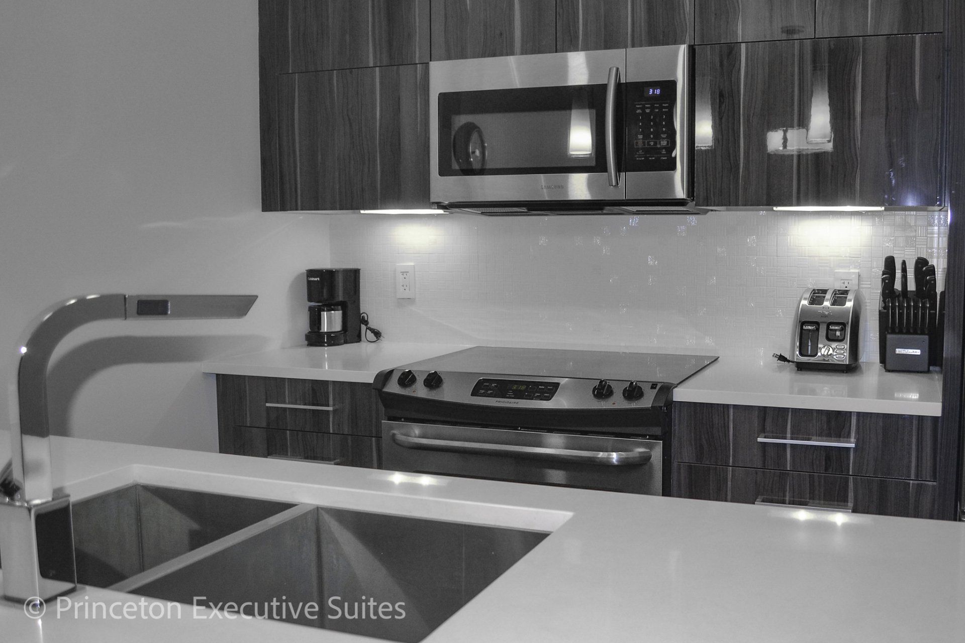 Stainless steel appliance with ceramic cooktop stove and white quarts countertop in this very modern edmonton executive suite