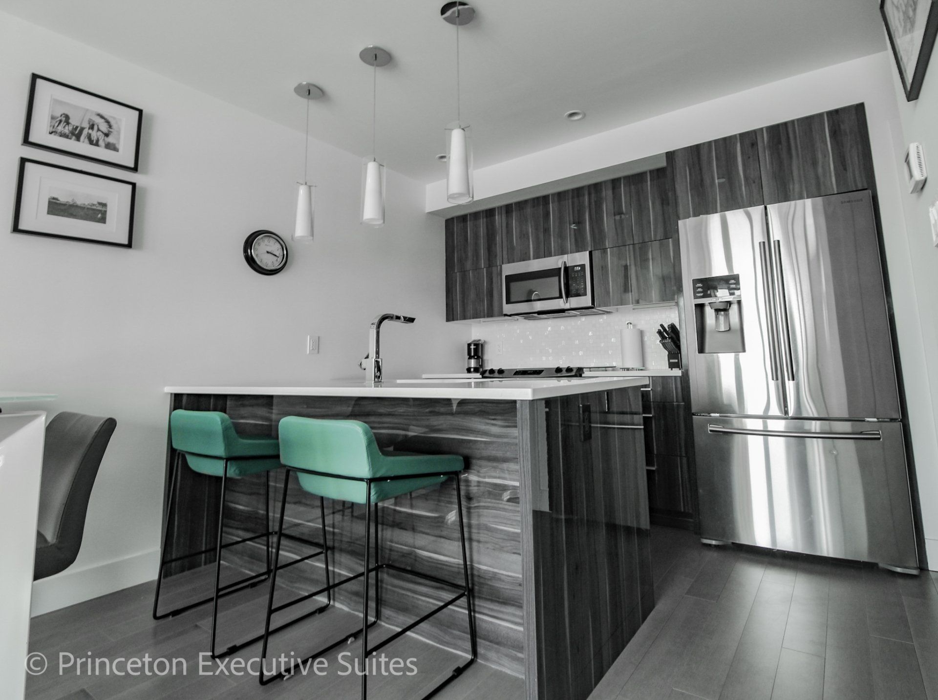 Turquoise and black barstools in front of a grey gloss eating bar with Quarts counter tops and stainless steel kitchen in the back ground of this Edmonton executive suite