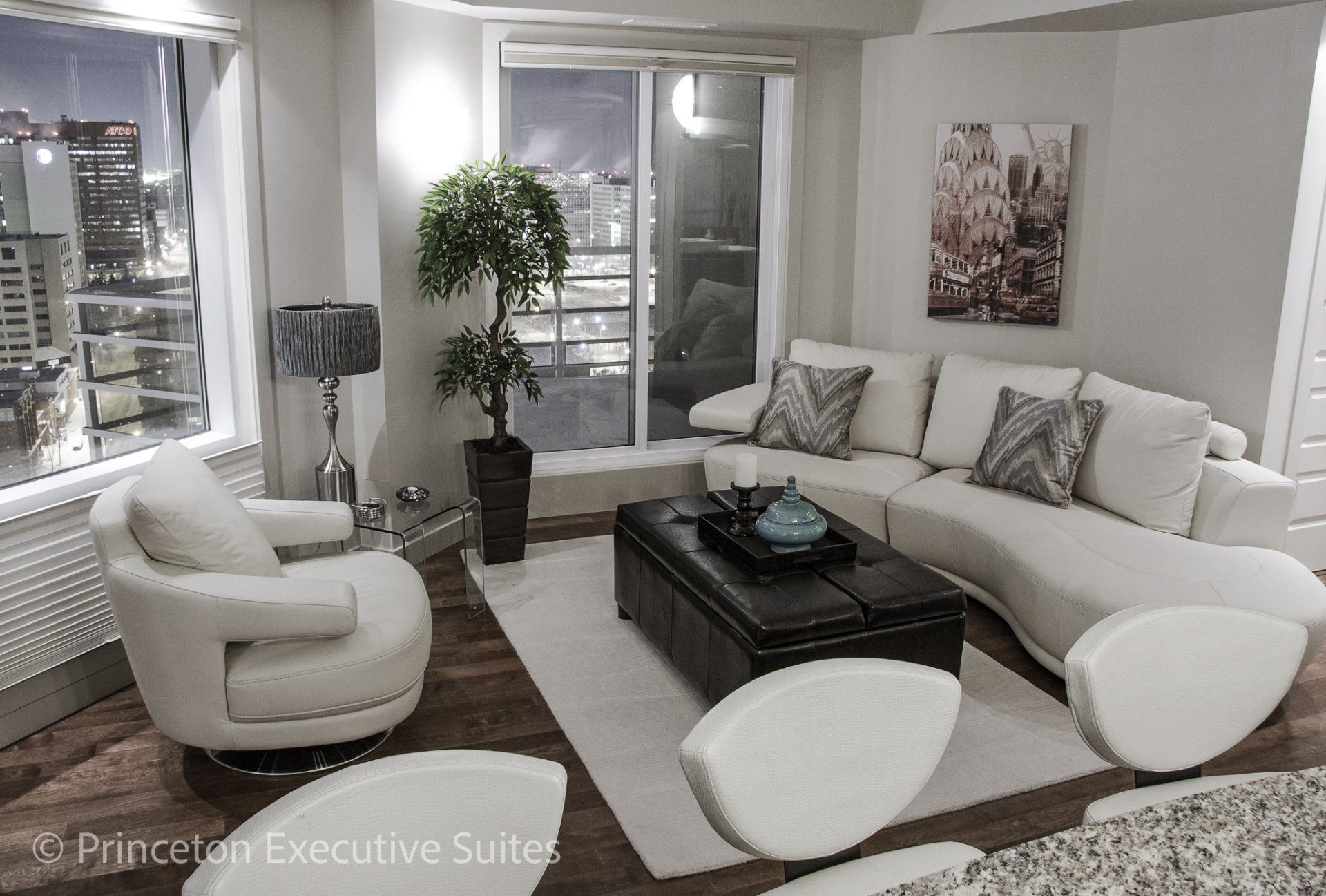 Living room with white rounded sectional couch and chair in a Edmonton furnished luxury suite