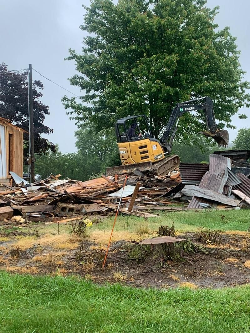 A bulldozer is demolishing a house in a grassy field.