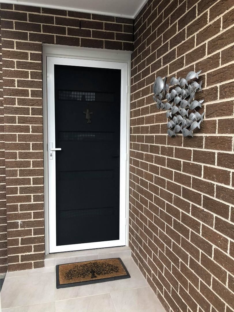 A Brick Wall With A Black Door And A Door Mat — Central Coast Flyscreen Service In West Gosford, NSW