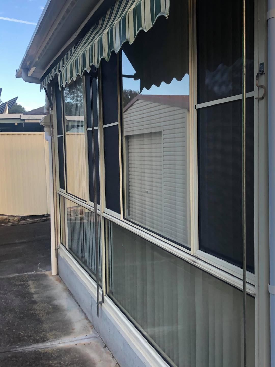 A House With A Striped Awning On The Windows — Central Coast Flyscreen Service In Warnervale, NSW