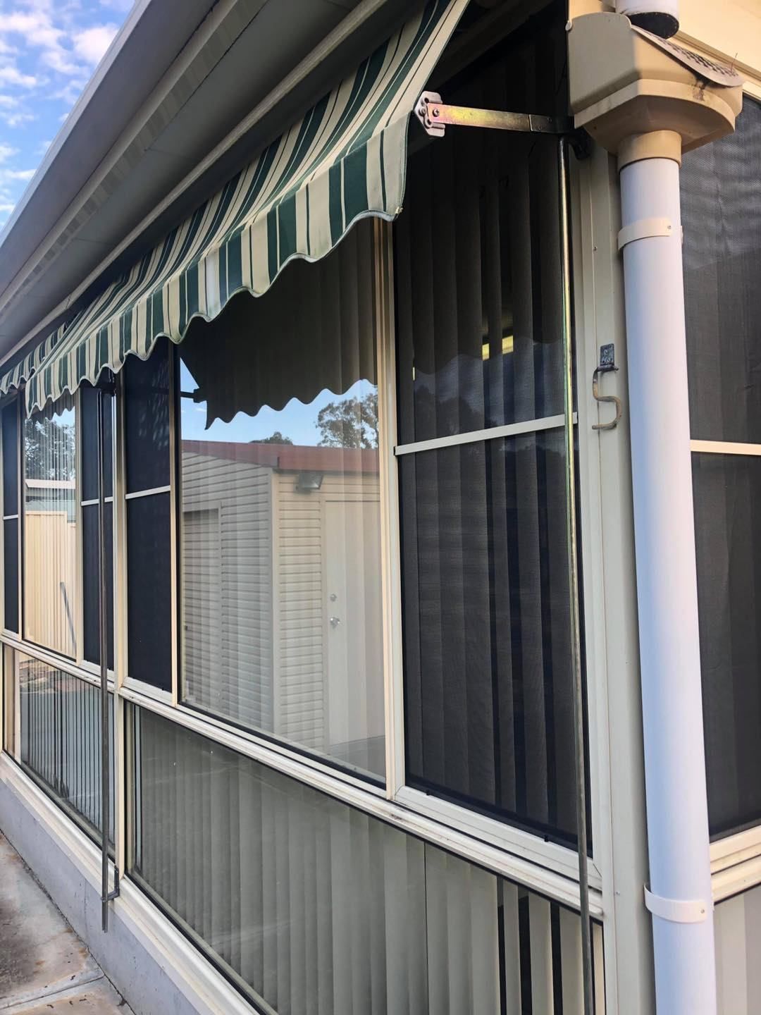 A House With A Striped Awning Over The Windows — Central Coast Flyscreen Service In Wyee, NSW