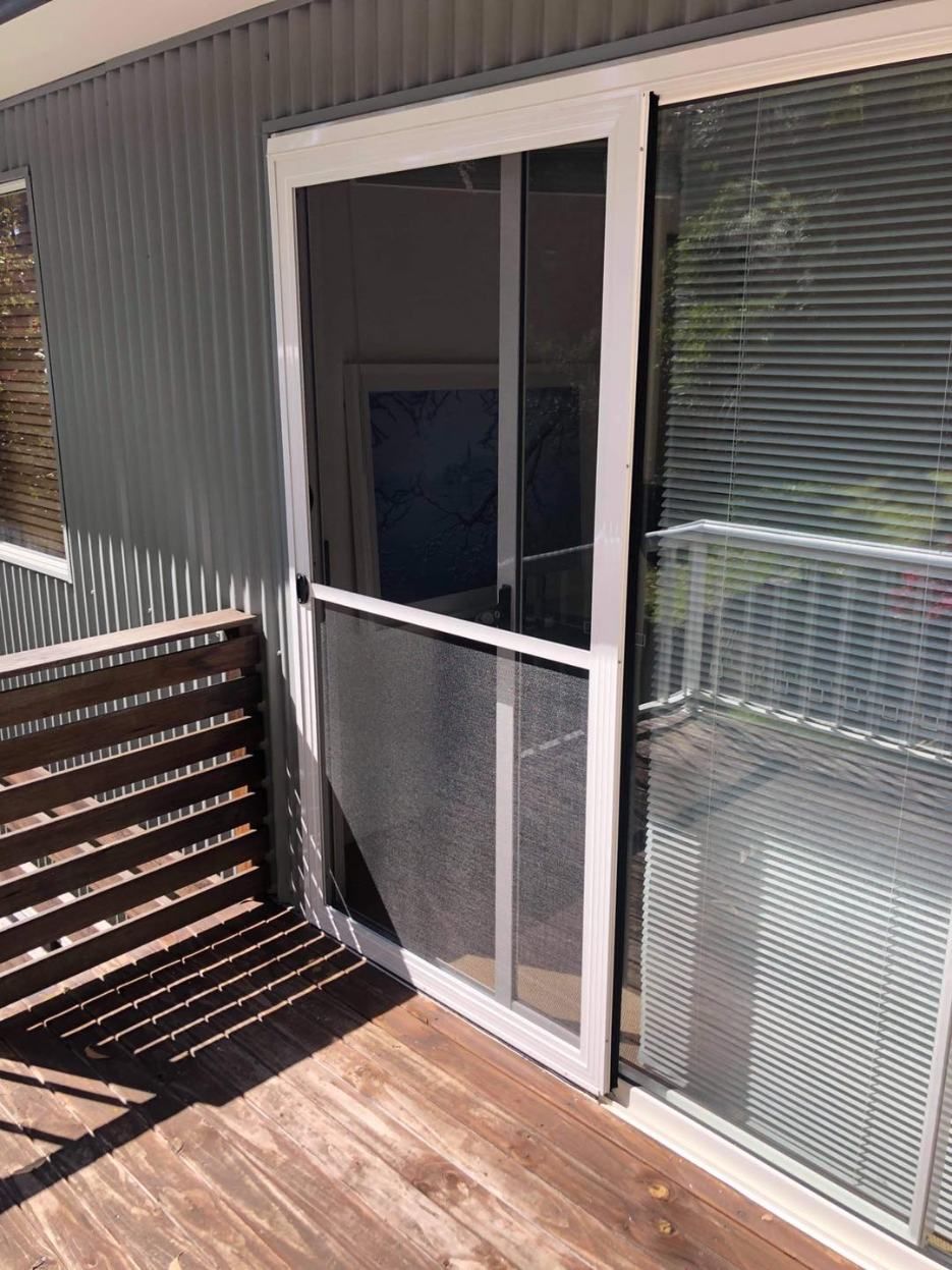 A Sliding Glass Door With A Screen On It Is On A Balcony — Central Coast Flyscreen Service In Warnervale, NSW
