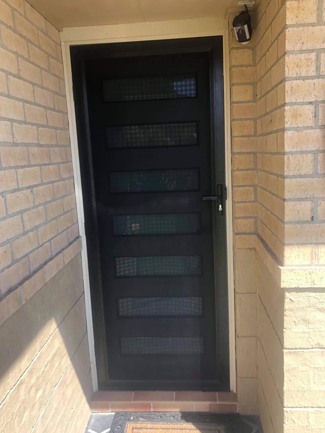 A Black Door Is On The Side Of A Brick Building — Central Coast Flyscreen Service In Wyee, NSW