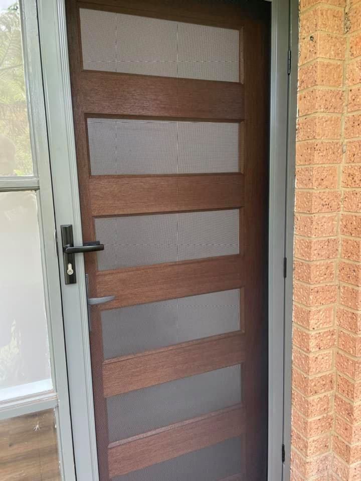 A Wooden Door With A Screen On It Is Sitting Next To A Brick Wall — Central Coast Flyscreen Service In Warnervale, NSW