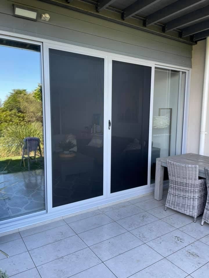 A Patio With A Sliding Glass Door And A Table And Chairs — Central Coast Flyscreen Service In Wyee, NSW