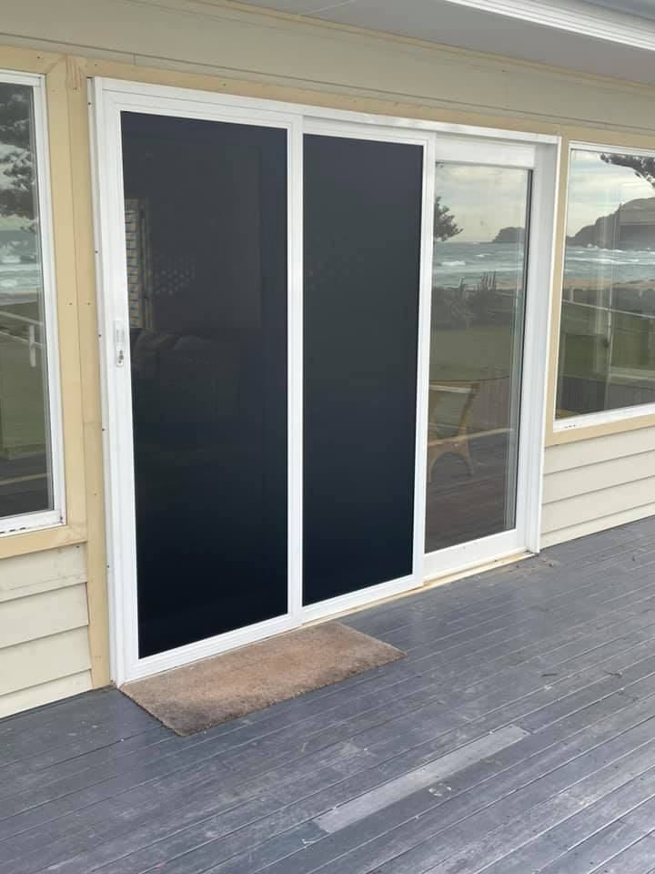 A Sliding Glass Door With A Black Screen Is On A Deck — Central Coast Flyscreen Service In Woongarah, NSW