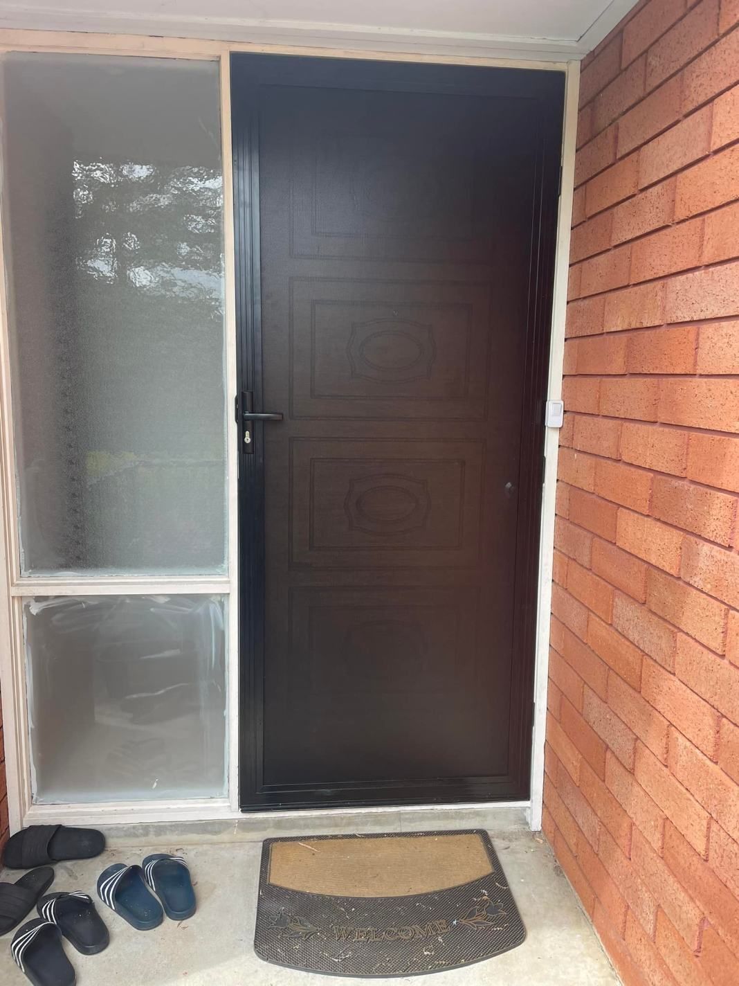 A Door With A Brick Wall And A Door Mat In Front Of It — Central Coast Flyscreen Service In Wyee, NSW