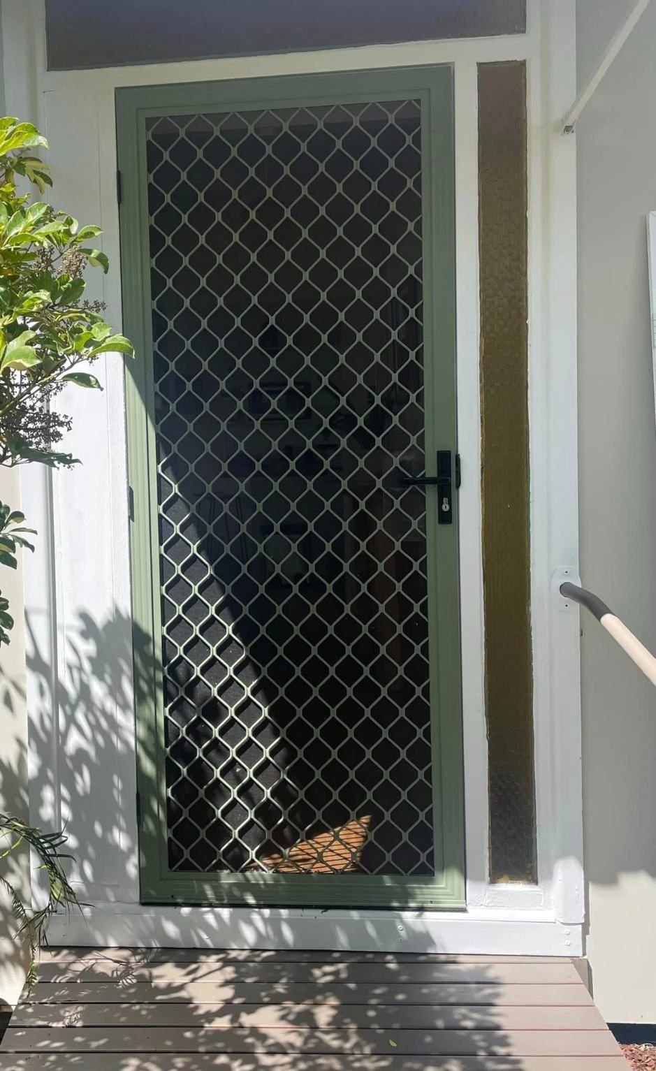 A Green Screen Door Is Sitting On Top Of A Wooden Deck — Central Coast Flyscreen Service In Woy Woy, NSW
