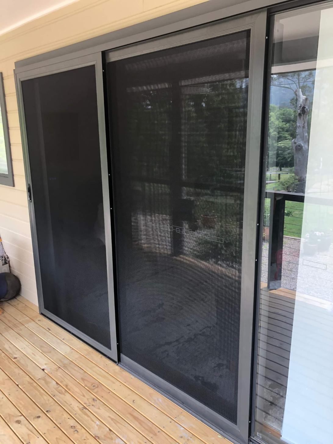 A Sliding Glass Door With A Screen On It Is On A Wooden Deck — Central Coast Flyscreen Service In Wyee, NSW