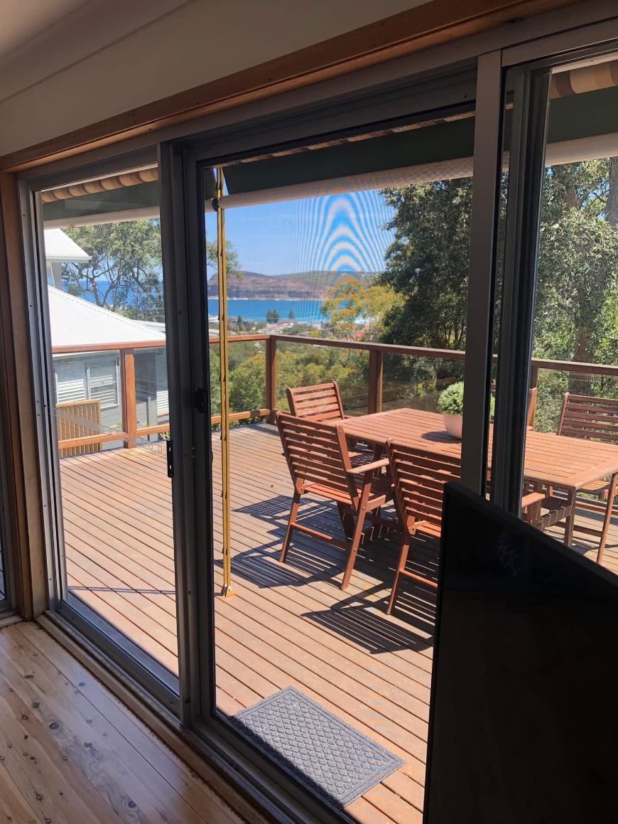A Sliding Glass Door Leading To A Deck With A Table And Chairs — Central Coast Flyscreen Service In West Gosford, NSW