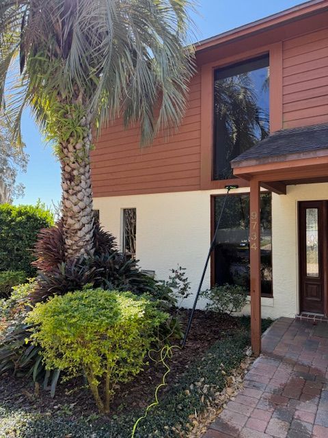 Person in pink glove wiping a window with a pink and tan cloth.