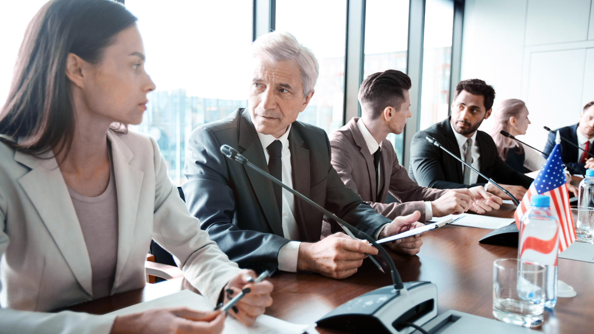 A group of business people are sitting at a table with microphones.