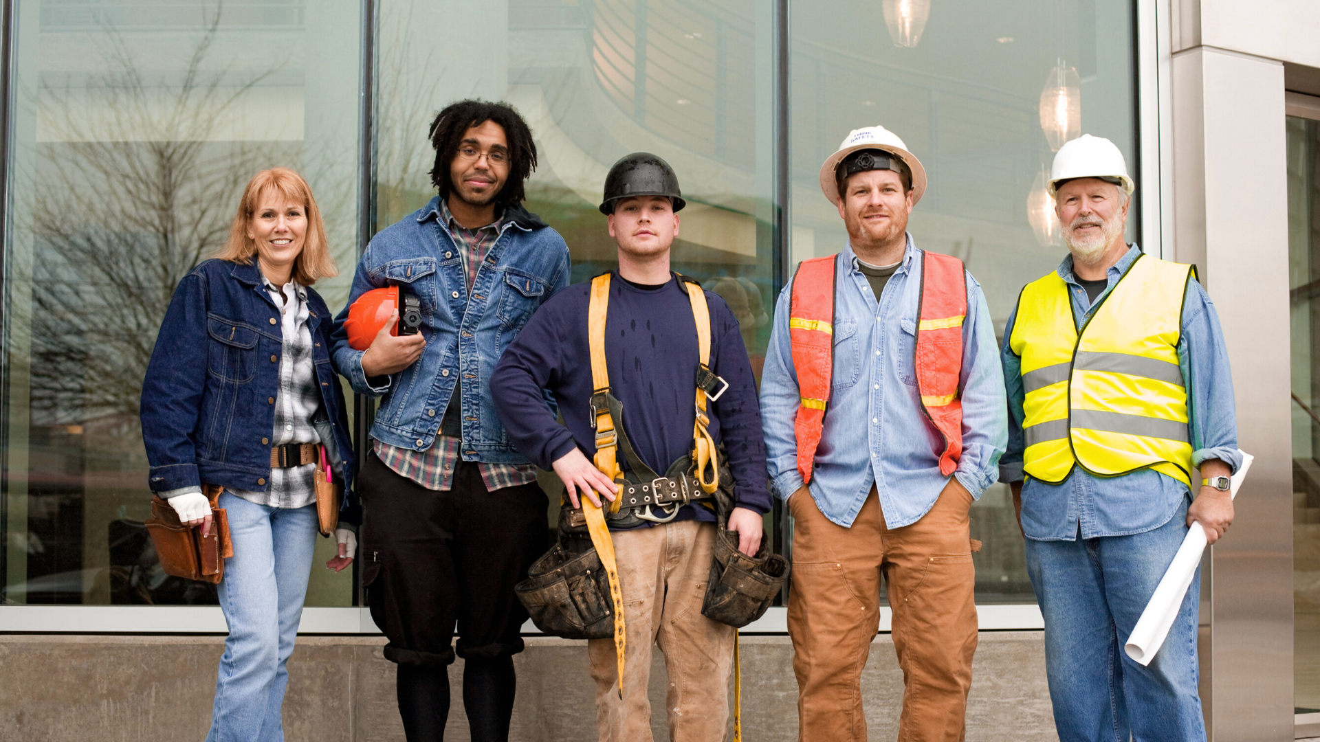 A group of construction workers are posing for a picture in front of a building.