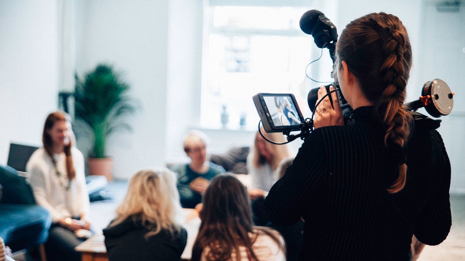 A woman is holding a camera in front of a group of people.