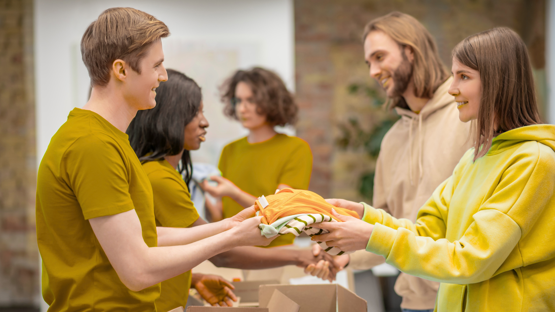 A group of people are giving clothes to each other in a room.