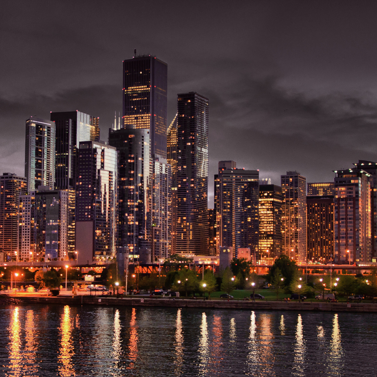 A city skyline at night with a body of water in the foreground