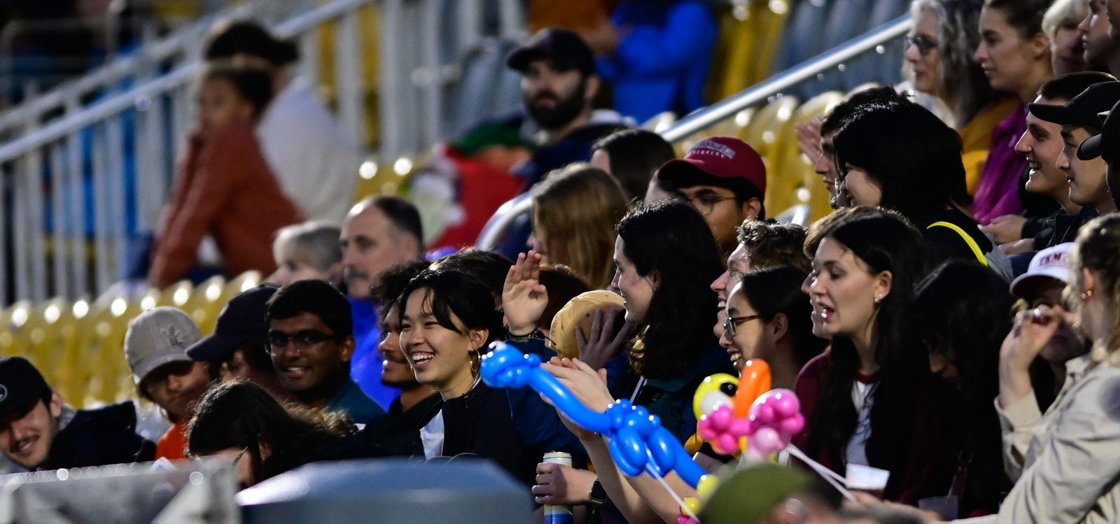 Fans laughing in the stadium with balloon animals