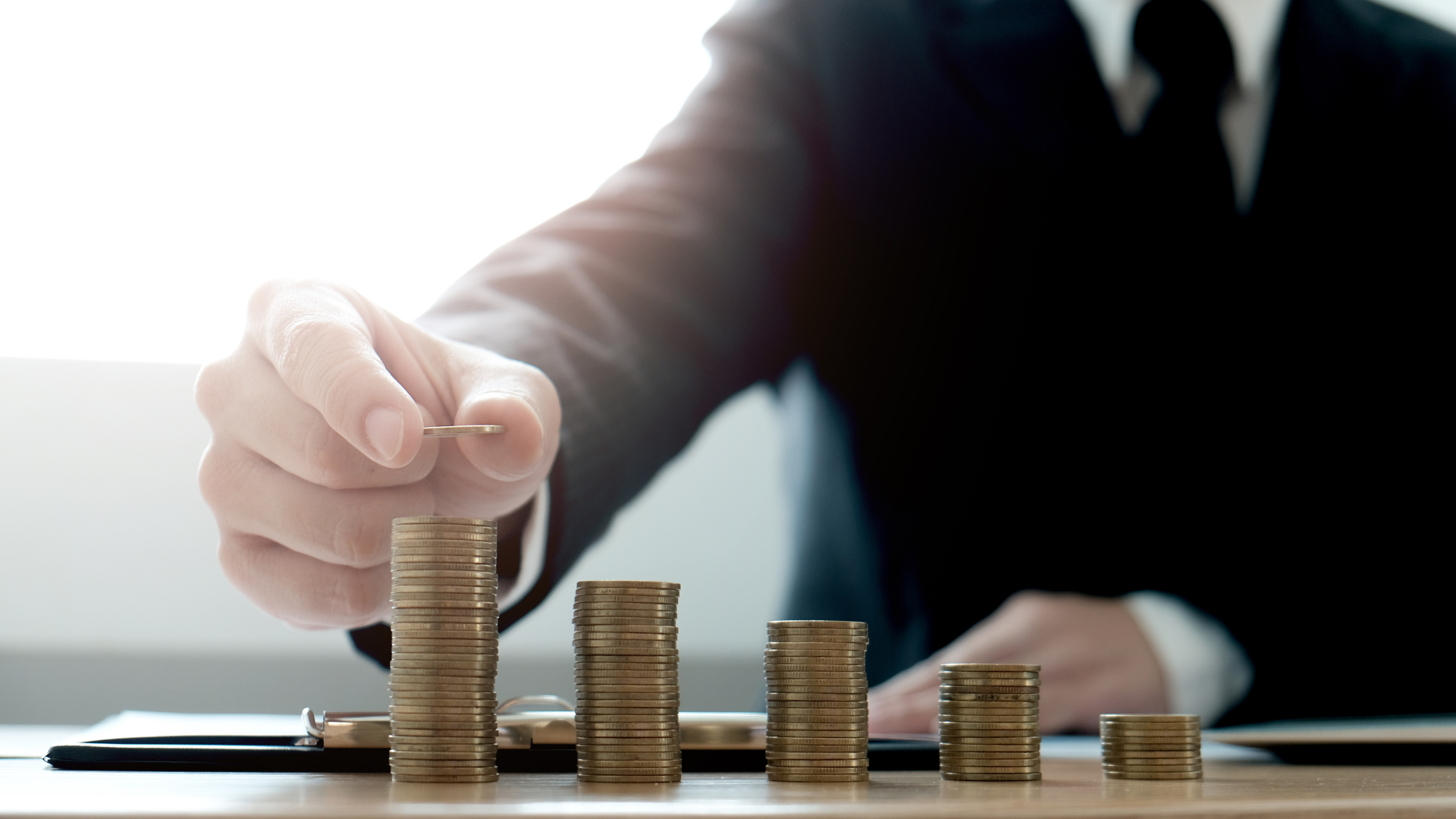 A man is stacking coins on top of each other on a table.