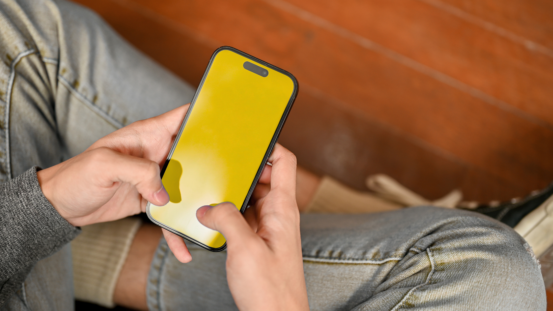 A person is sitting on the floor using a cell phone.