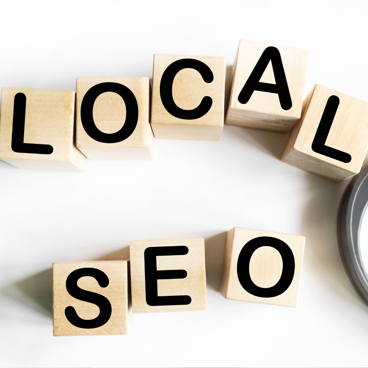 The word local seo is written on wooden blocks next to a magnifying glass.