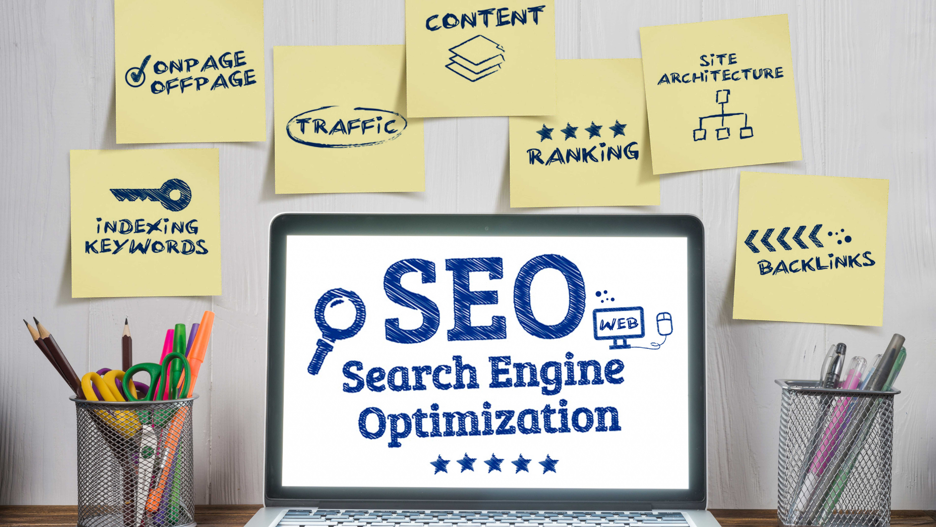 A laptop computer is sitting on a desk with sticky notes on the wall that say seo search engine optimization