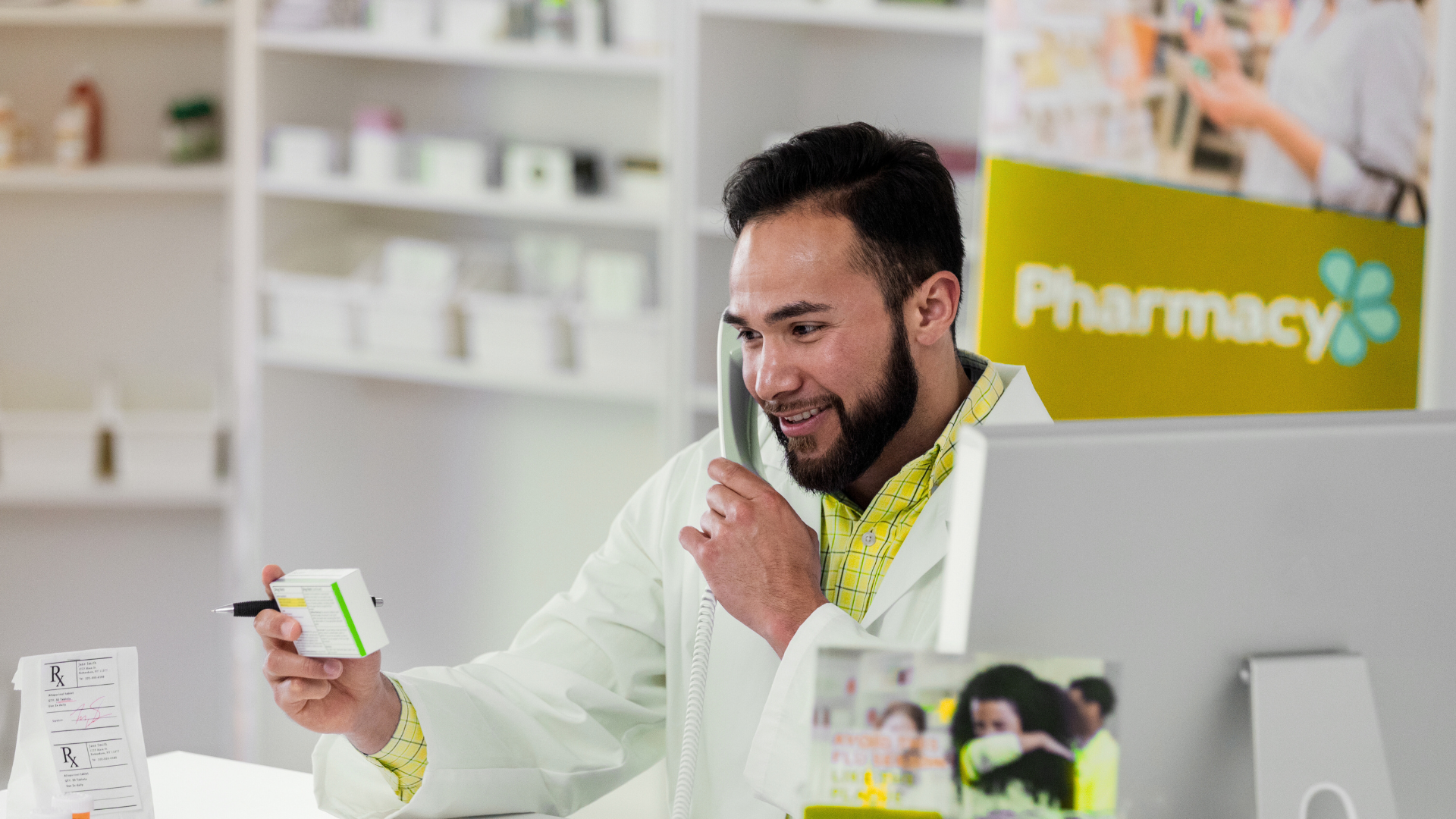 A pharmacist is talking on a cell phone while holding a bottle of pills.