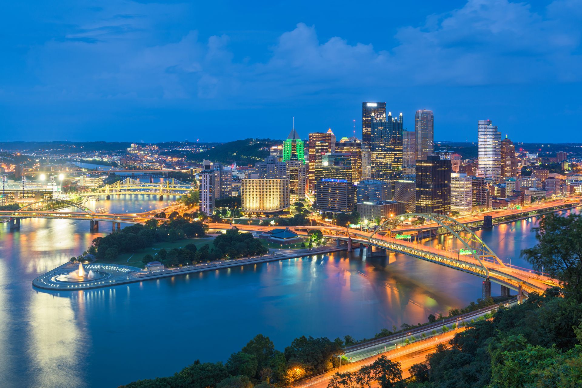 An aerial view of a city at night with a river in the foreground.