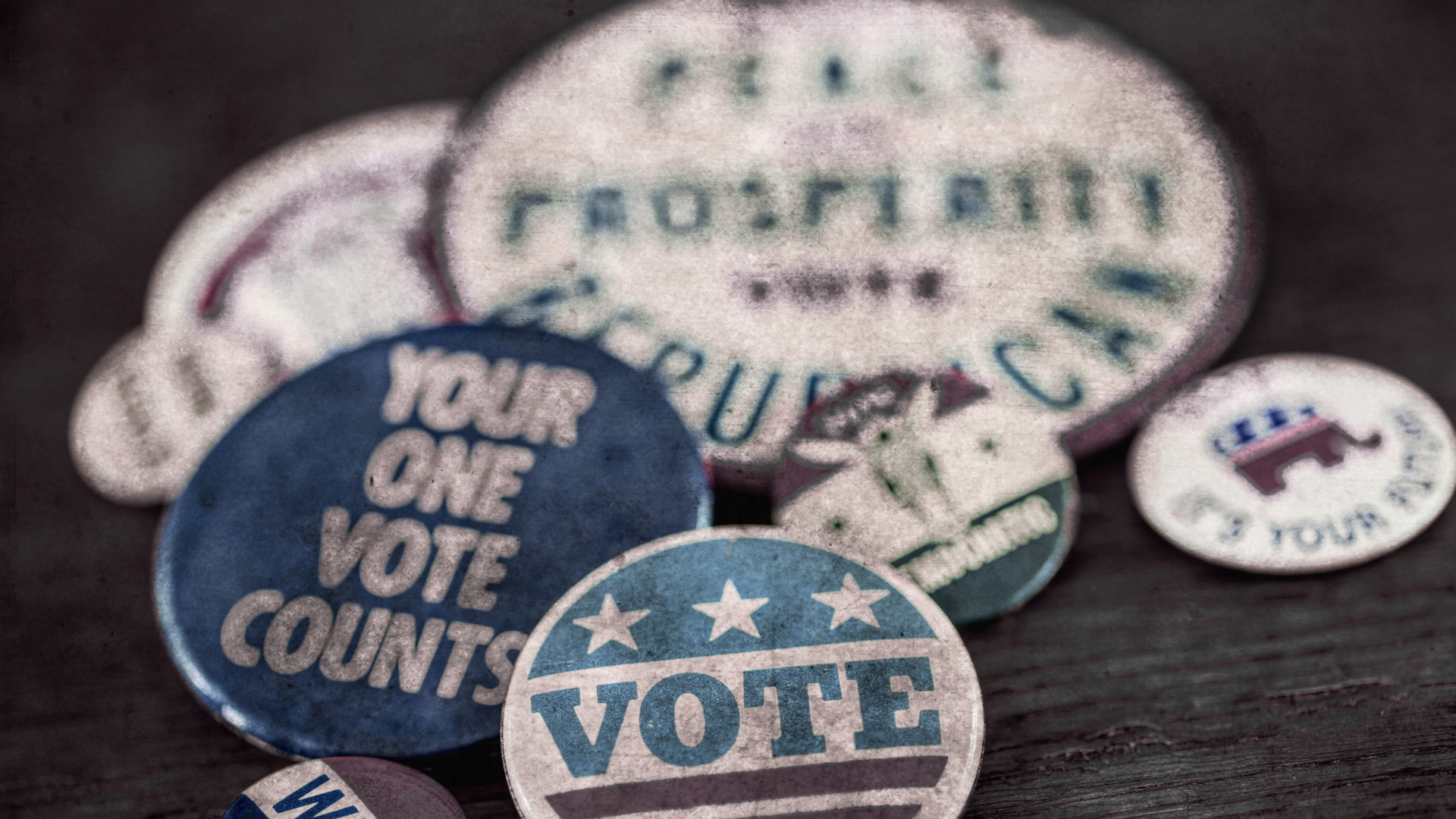 A bunch of buttons on a table with one that says `` your one vote counts ''.