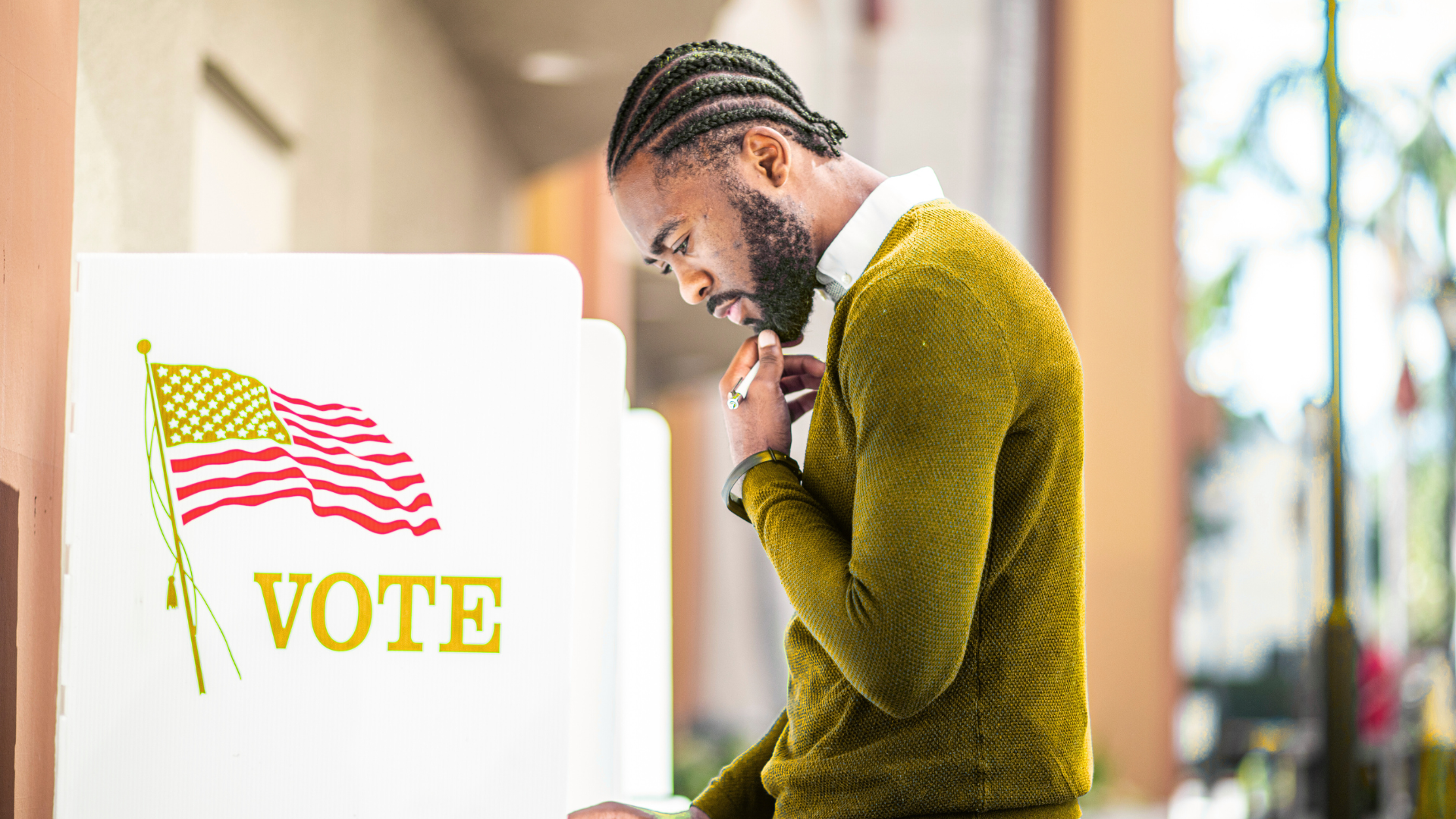 A man is standing in front of a voting booth.