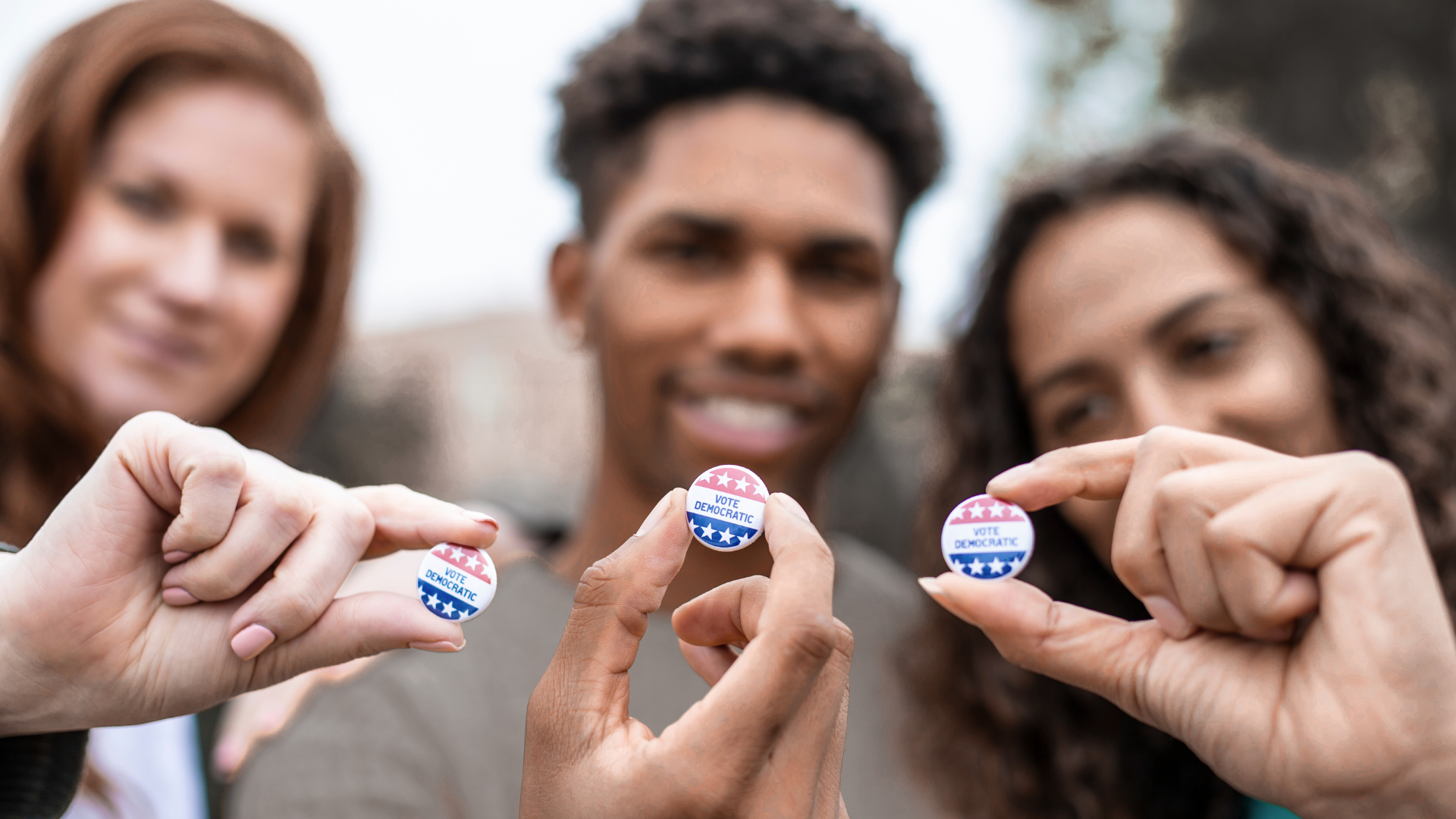 A group of people are holding small buttons in their hands.