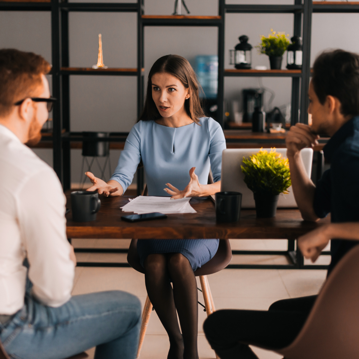 A woman is sitting at a table talking to two men