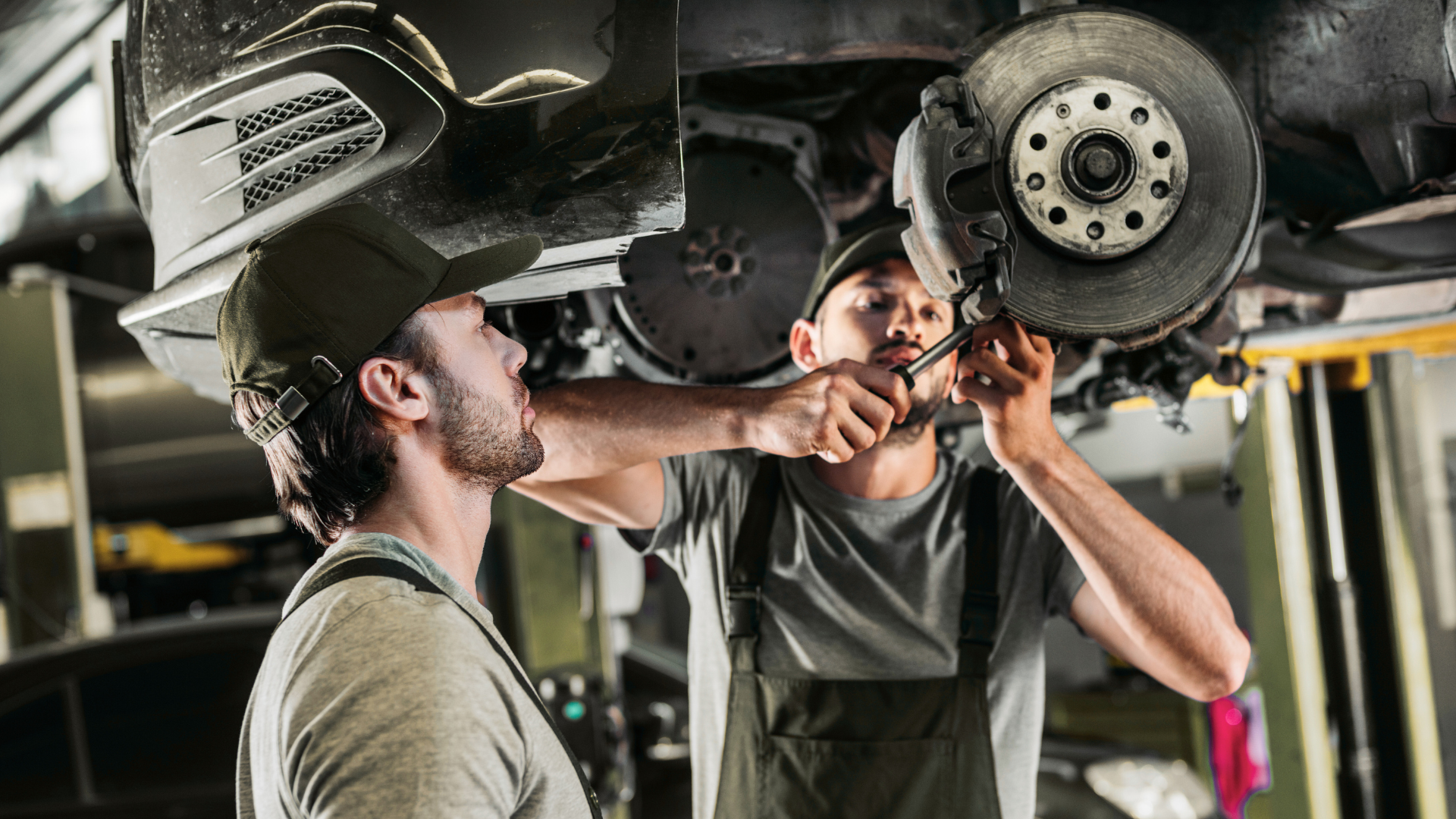 Two men are working on a car in a garage.
