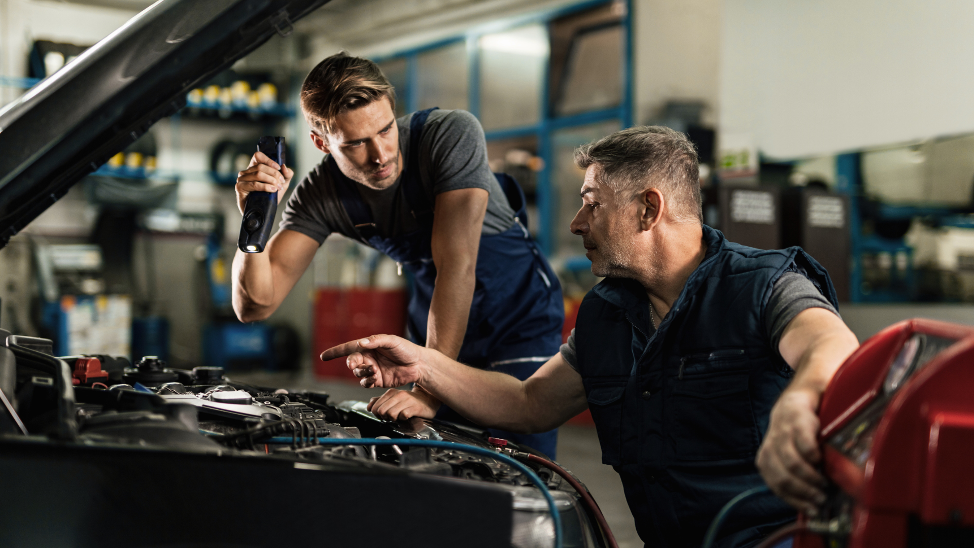 Two mechanics are working on a car in a garage.