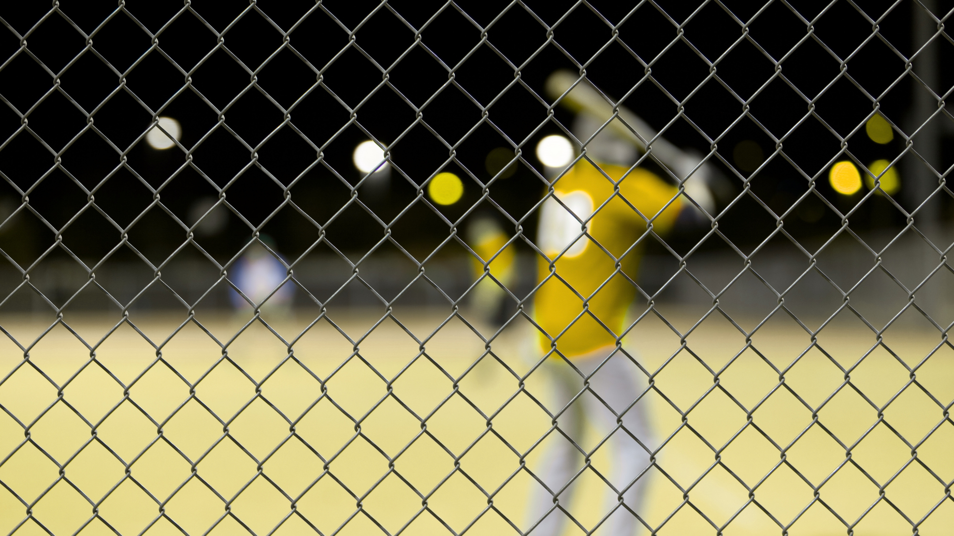 A blurry picture of a baseball player behind a chain link fence