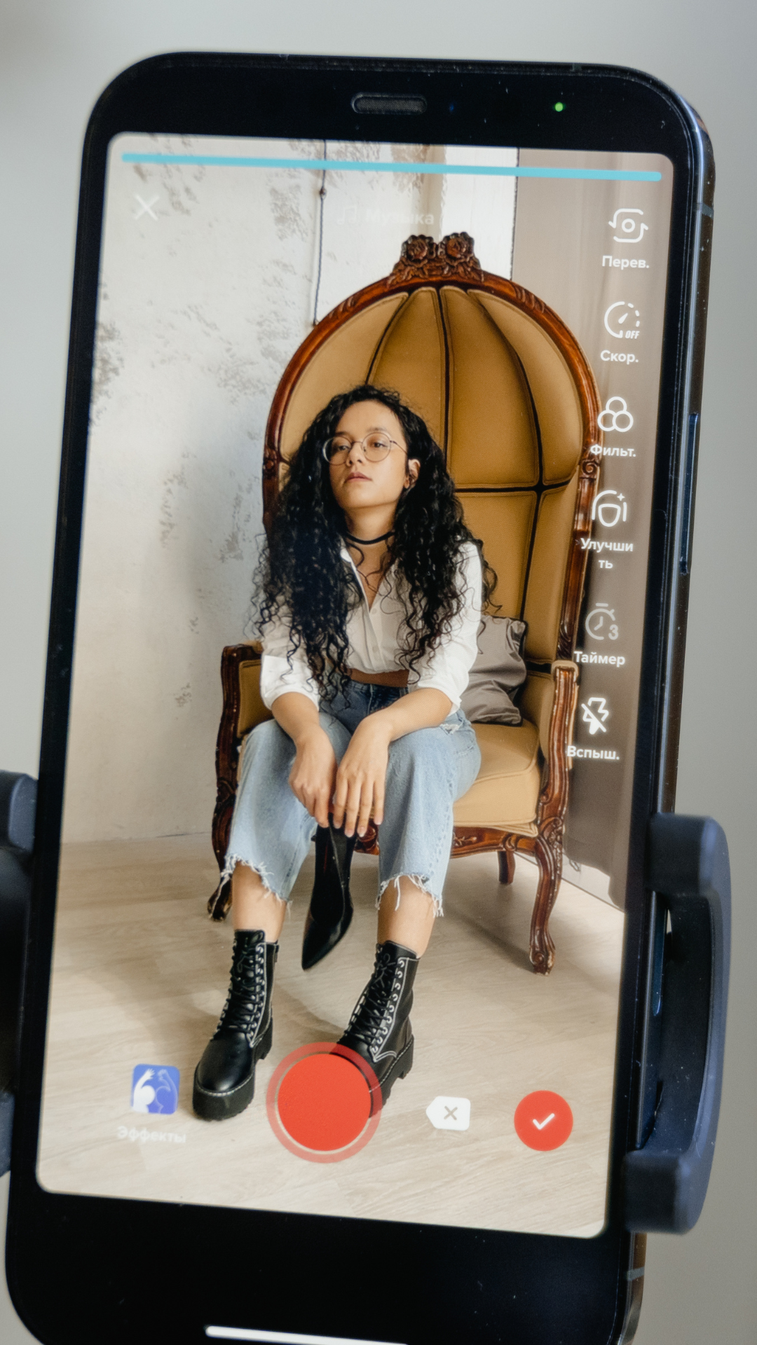 A woman is sitting in a chair on a cell phone.
