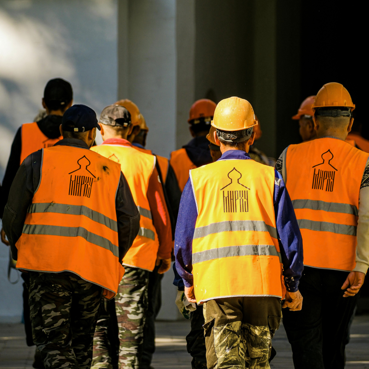 A group of construction workers wearing orange vests and hard hats