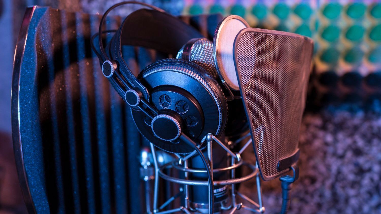 A pair of headphones sitting on top of a microphone in a recording studio.