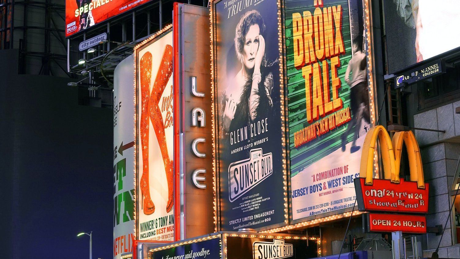 A busy city street with a mcdonald 's and a broadway sign.