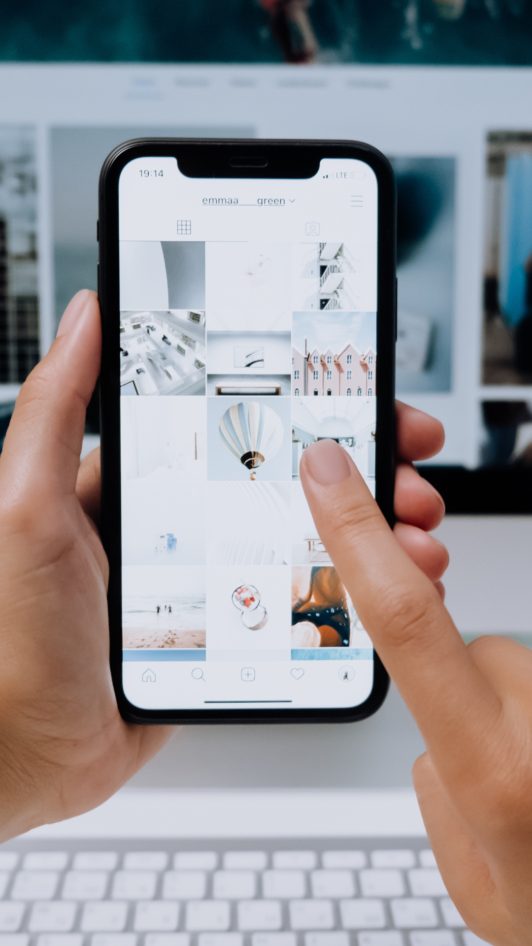 A person is holding a cell phone in their hand and pointing at it.
