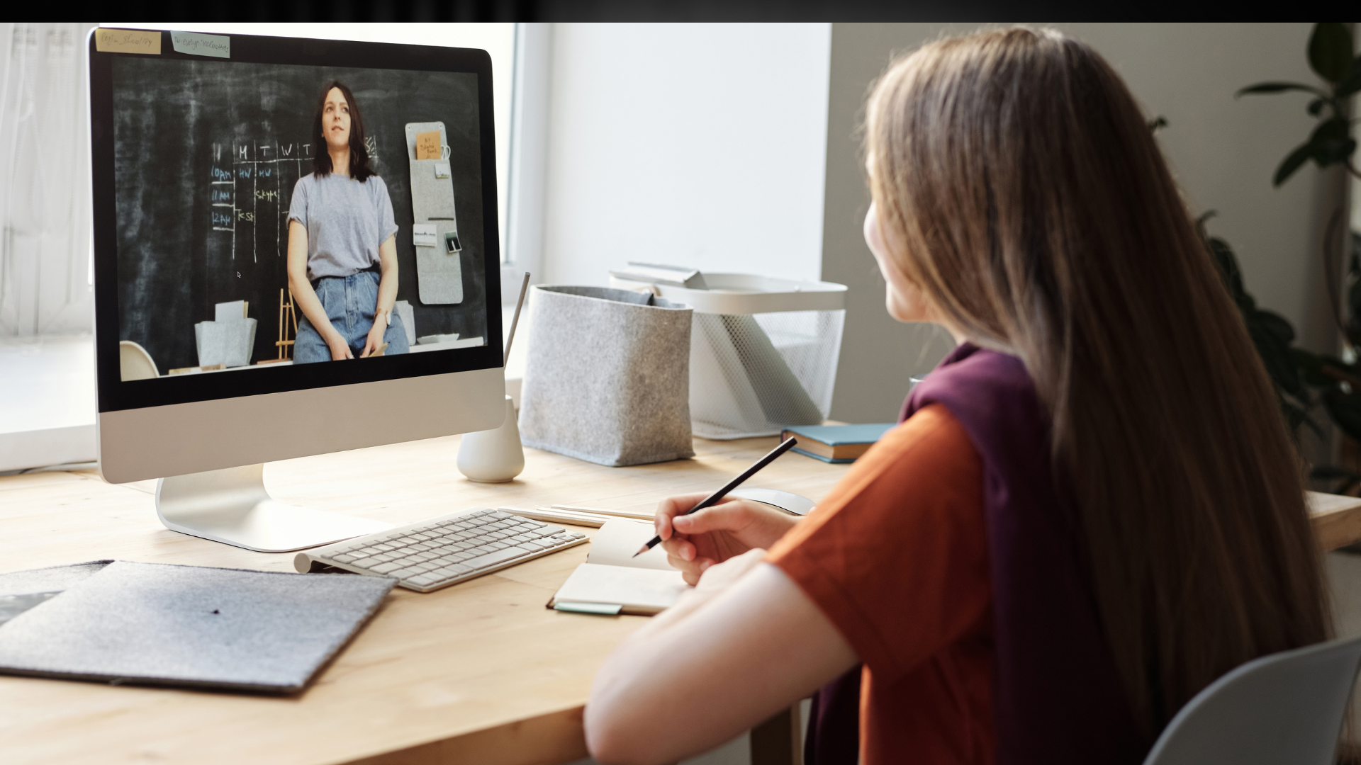 A woman is sitting at a desk looking at a computer screen.