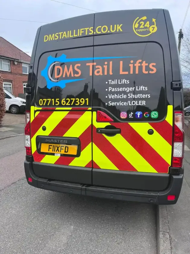 Rear of a black DMS Tail Lifts service van with red and yellow reflective chevrons, phone number, and services listed.