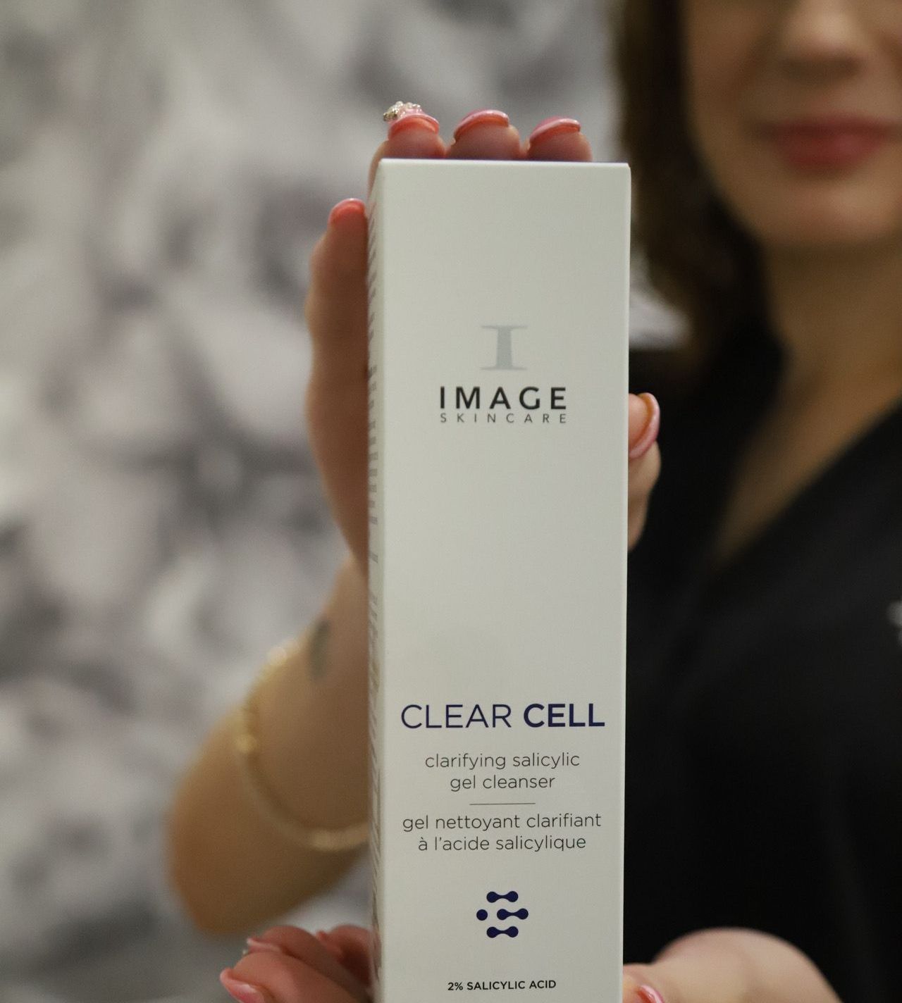 A woman is holding a box of clear cell lotion