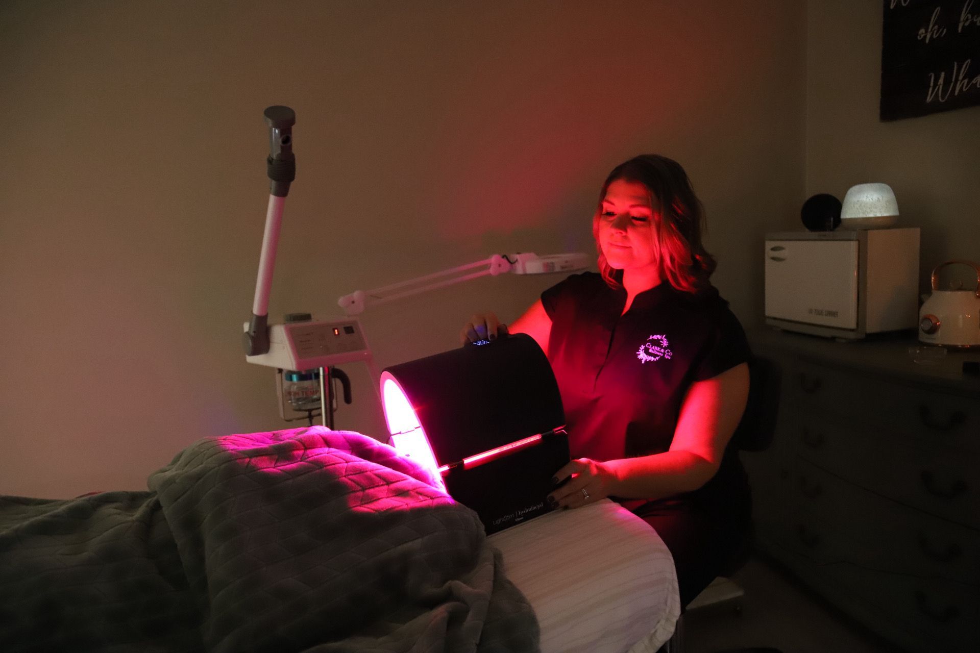 Woman administering red light therapy to a patient in a spa.